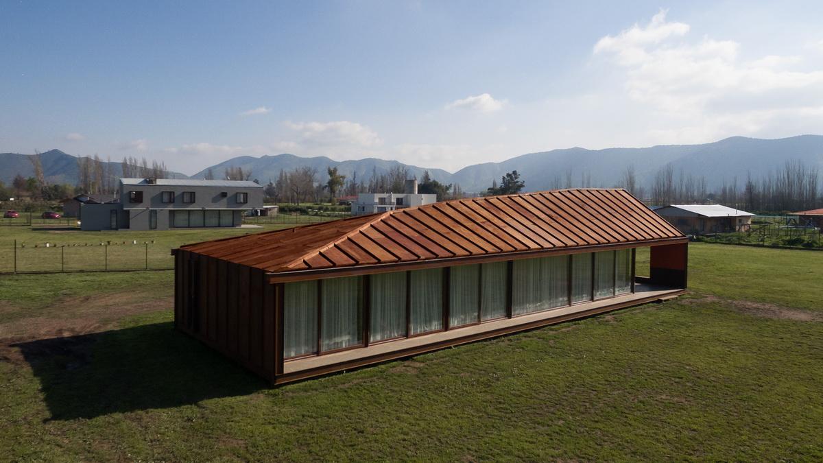 乡村草地上的红色棚屋：PH2住宅 / DX Arquitectos